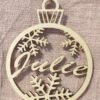 Boule de Noël Personnalisée en Bois Prénom "Julie" (Flocons) Ajoutez une touche unique à votre sapin avec cette magnifique boule de Noël en bois clair. Découpée au laser avec précision, elle arbore le prénom "Julie" (ou votre choix) au centre, entouré de délicats flocons de neige. Parfait pour un cadeau personnalisé mémorable ou une décoration de style rustique chic. Livrée avec sa cordelette en jute naturelle.